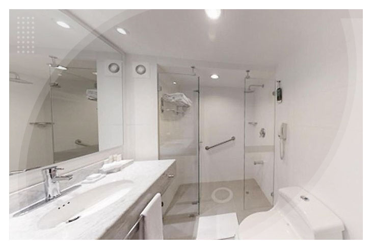 Baño moderno con ducha en vidrio, lavamanos amplio, inodoro y acabados blancos, en una de las habitaciones a las cuales se puede acceder con reservas en el hotel La Fontana a bajo precio