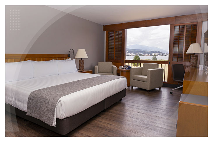 Habitación amplia con cama doble, escritorio, sillones y gran ventanal con vista natural en los hoteles de Paipa con descuento