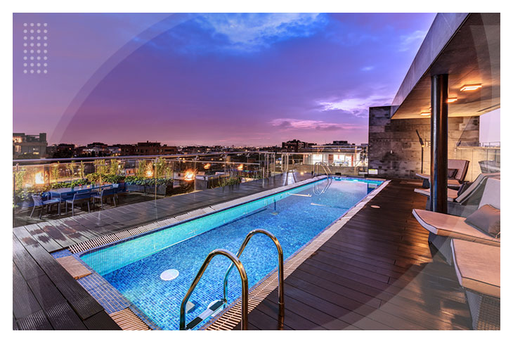 Piscina en la terraza con vista panorámica al atardecer, rodeada de sillas reclinables y un ambiente moderno y tranquilo, ubicada en uno de los hoteles de Bogotá cerca del Parque de la 93