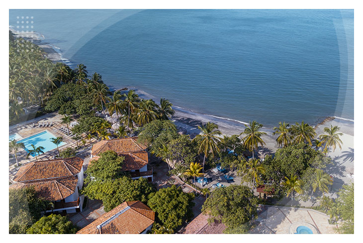 Vista aérea del hotel que tiene techos de teja color rojo rodeados de palmeras, con acceso directo a la playa y zonas húmedas, una opción perfecta de los hoteles en Santa Marta con descuento