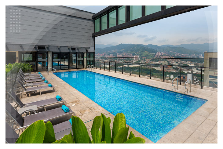 Piscina ubicada en la terraza del hotel, rodeada de sillas asoleadoras con vista de las montañas y la ciudad, una de las experiencias destacadas al hacer la reserva en el Hotel Estelar Square al mejor precio