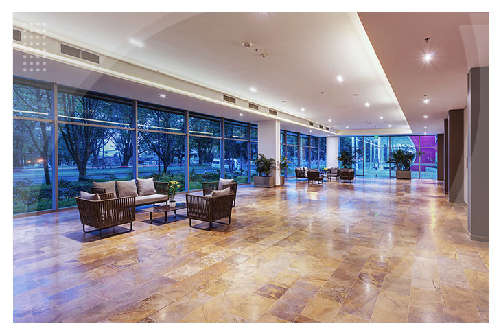 Lobby amplio con pisos en tonos cálidos, sillones modernos y grandes ventanales que permiten la entrada de luz natural, ideal para quienes buscan los mejores hoteles en Villavo