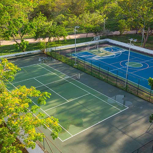 Dos canchas una de tenis de piso verde y una de baloncesto con piso azul, rodeadas de naturaleza, las cuales se pueden conocer al comprar el plan fin de semana festivo en Lagosol