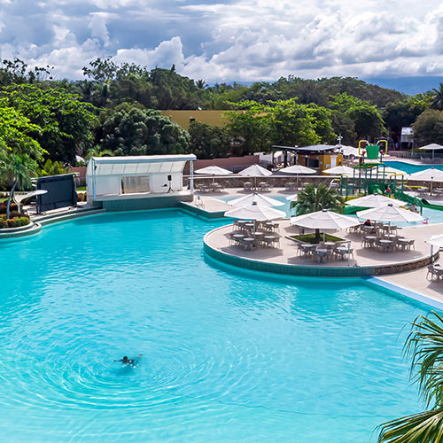Piscinas, palmeras y mesas playeras de las instalaciones donde se reservan los planes de fin de semana del Hotel Lagosol