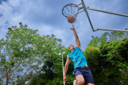 Hombre que usa ropa deportiva salta para encestar el balón de básquet en el aro de una cancha a la que se puede acceder con las mejores tarifas de los planes del hotel Lagosol